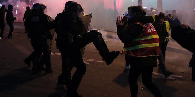 Ein Polizist tritt in Paris auf einen Demonstranten in gelber Warnweste ein