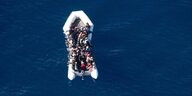Migranten sitzen in einem Schlauchboot im Mittelmeer
