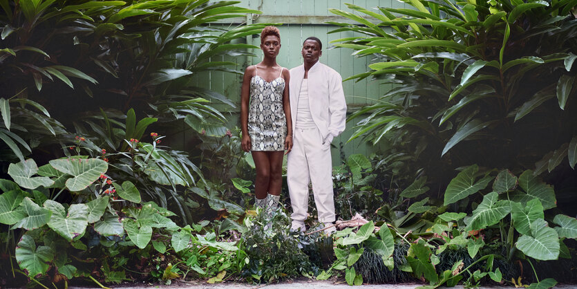 Queen (Jodie Turner-Smith) und Slim (Daniel Kaluuya) stehen in mitten von Pflanzen. Queen trägt ein kurzes Kleid, slim einen weißen Anzug.