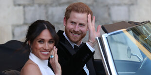 Harry und Meghan sitzen im Auto und winken