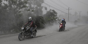 Mtorräder fahren über eine mit Asche bedeckte Straße