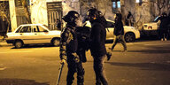 Ein Polizist und ein Demonstrant stehen sich auf einer nächtlichen Strasse gegenüber