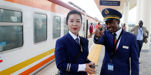 Zwei SchaffnerInnen stehen auf einem Bahnsteig in Kenia