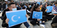Demonstranten halten uigurische Fahnen