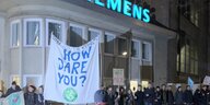Vor dem Siemens Gebäude hängt ein weißer Banner mit der Aufschrift "How dare you?", Aktivisten formen eine Menschenkette