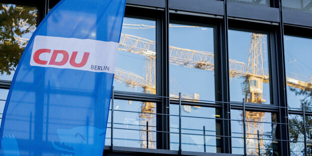 CDU Fahne vor sich spiegelnden Baukränen
