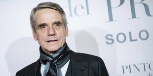 Jeremy Irons steht vor einer Wand