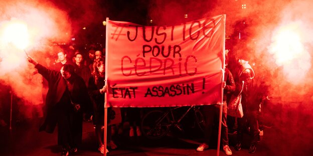 Demonstranten tragen ein Transparent, auf dem auf französisch "#Gerechtigkeit für Cédric" und "Mörder-Staat" steht