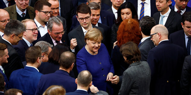 Angelas Merkel wirft bei der Abstimmung zur Reform der Organspende ihren Zettel ein. Sie ist dabei dicht umringt von anderen Parlamentariern