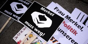 Plakate von Pegida liegen gestapelt auf der Straße.