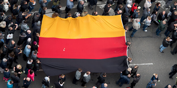Teilnehmer einer Demonstration tragen eine Deutschlandfahne