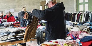 Ein Mann sucht Kleider von einem Stapel aus