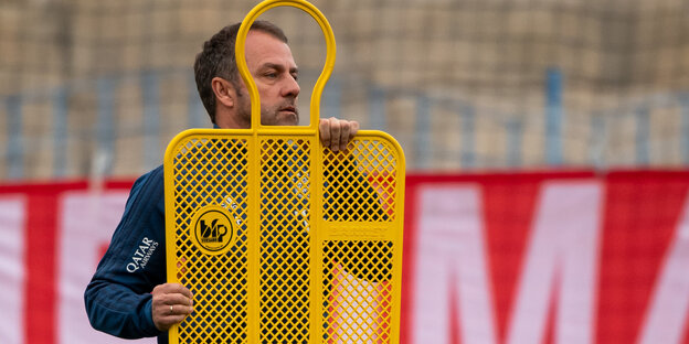 Bayern-Trainer Hansi Flick trägt eine Aufstellfigur