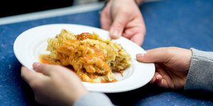 ein kind hält einen Teller mit essen in der Hand