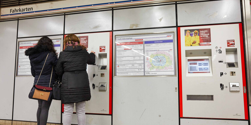 Frauen stehen vor einem Fahrkartenautomaten