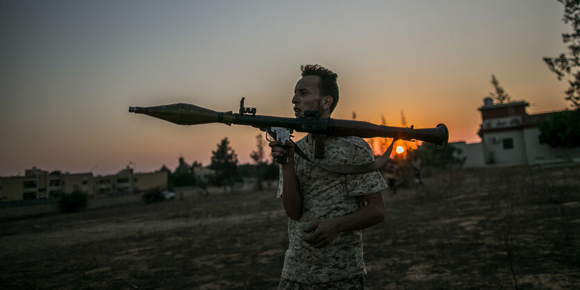 Einbewaffneter Kämpfer der international anerkannten Regierung. Er trägt eine Uniform mit kurzen Ärmeln und eine Waffe auf der Schulter.