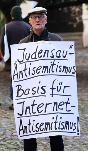 Michael Düllmann protestiert mit einem Plakat für die Entfernung eines antisemitischen Reliefs an der Stadtkirche Wittenberg.