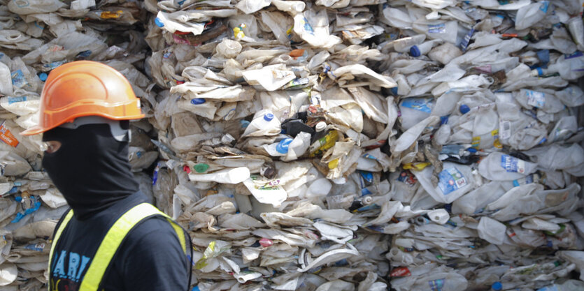 Ein Mann steht vor gepresstem Plastikmüll