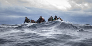 Flüchtende auf einem Boot im Wasser, die Kameraperspektive ist auf Höhe des Wasserspiegels
