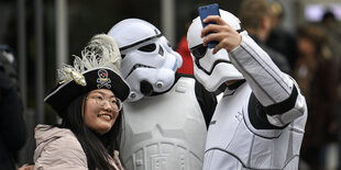 Die aus der Science-Fiction-Filmreihe bekannten schwarz-weißen Sturmtruppler-Rüstung knipsen ein Selfie mit einem Fan