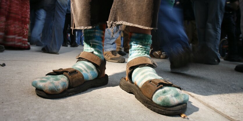 Füße, in Socken und Sandalen, darüber eine braune Kordhose