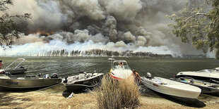 Boote liegen am Strand, im Hintergrund die Aschewolken der Buschfeuer