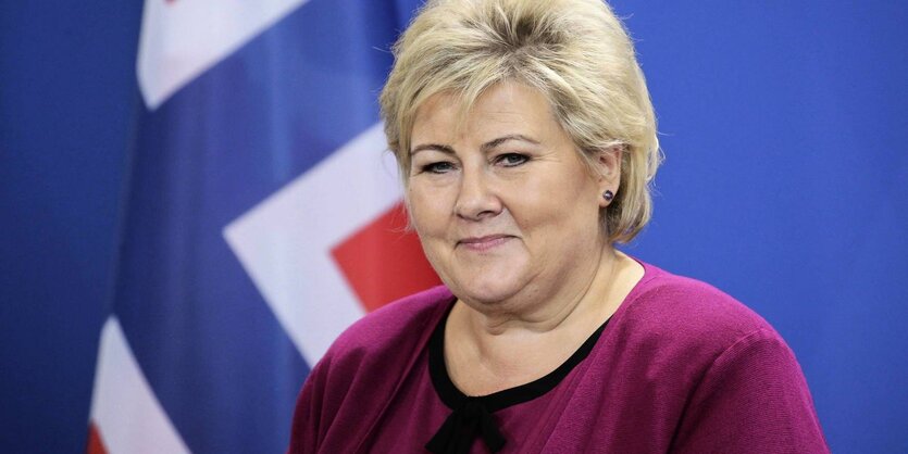 Die norwegische Ministerpräsidentin Erna Solberg vor einer norwegischen Flagge.