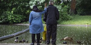 Zwei ältere Menschen füttern Enten im Park