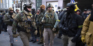 Bewaffnete Männer in Uniformen und mit Helmen stehen auf der Straße.