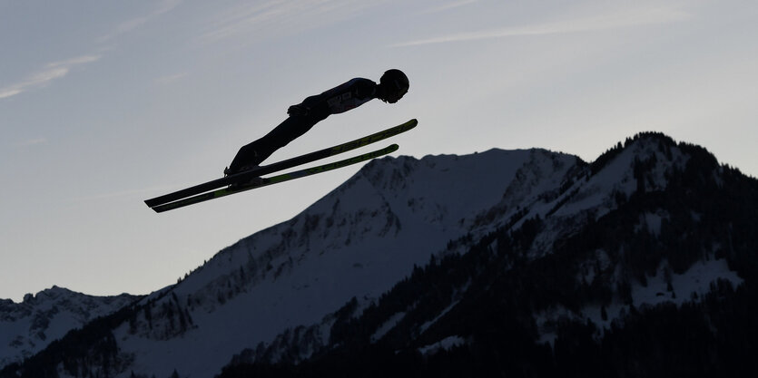 Skispringer vor einem Berg als Schattenriss