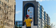Wandmalerei an einem Häuserblock, Junge schaut auf Luftballons