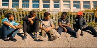 Mehrere Jungen sitzen auf einem Betonvorsprung in einer Banlieue