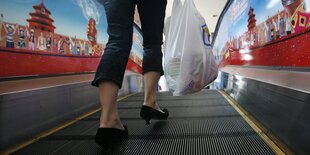 Frau mit einer Plastiktüte auf einer Rolltreppe