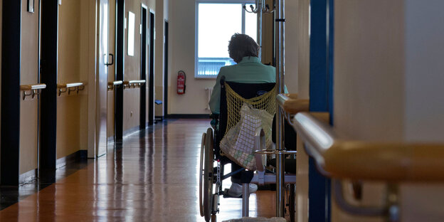 Eine ältere Frau sitzt in ihrem Rollstuhl im Flur eines Krankenhauses in Schwerin.