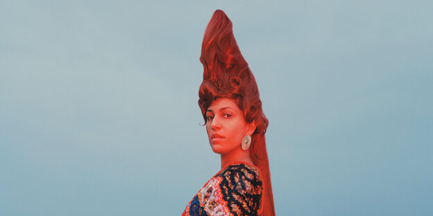 Die Musikerin Lafawndah mit hochstehender Turmfrisur mit roten Haaren in rötlichem Licht