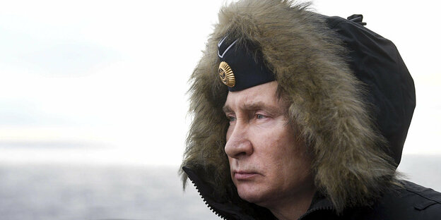 Wladimir Putin mit Militärmütze und Kapuze guckt in die Ferne