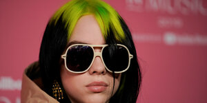 Billie Eiilish mit dunkler Sonnenbrille und froschgrüner Haarsträhne