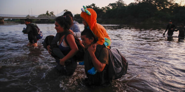 Eine Familie läuft durch den Fluss Suchiate