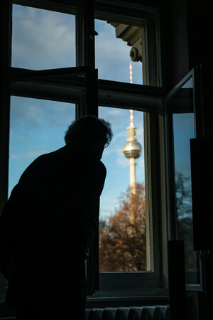 Kaufmann steht am Fenster, im Hintergrund der Fernsehturm