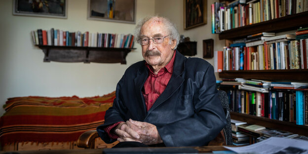 Walter Kaufmann sitzt vor seinem Bücherregal