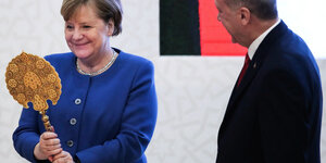 Bundeskanzlerin Angela Merkel steht neben Präsident Recep Tayyip Erdogan und hält einen Spiegel in den Händen.