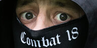 Ein Augenpaar, darunter ein Tuch mit Aufdruck "Combat 18"