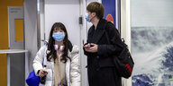 Zwei chinesische Reisende tragen Atemmasken am Flughafen in Finnland