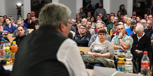 Im Vordergrund ist der brandenburgische Wirtschaftsminister zu sehen, im Hintergrund AnwohnerInnen von Gründheide und Umgebung