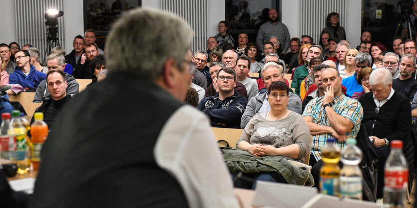 Im Vordergrund ist der brandenburgische Wirtschaftsminister zu sehen, im Hintergrund AnwohnerInnen von Gründheide und Umgebung