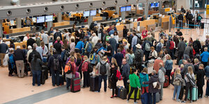 Zahlreiche Fluggäste warten auf dem Flughafen Hamburg vor Abfertigungsschaltern.