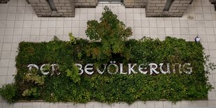 Schrift "Der Bevölkerung" ist überwuchert von grün