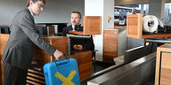 Ein mann stellt seinen Koffer auf ein laufband am Flughafen