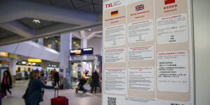 Plakat weist am Flughafen Tegel auf die Gefahren des Corona-Virus hin