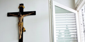 Ein Kreuz hängt an einer Wand in einer kirchlichen Einrichtung.